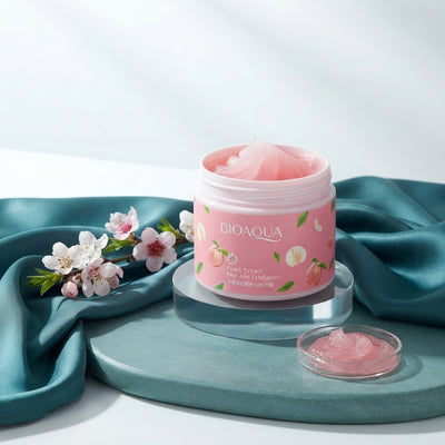 Peach Extract Exfoliating Face Gel bottle displayed on a teal stone surface with peach blossoms and teal silk fabric.